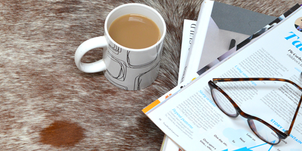 Coffee, magazines and glasses sit on top for a cow hide