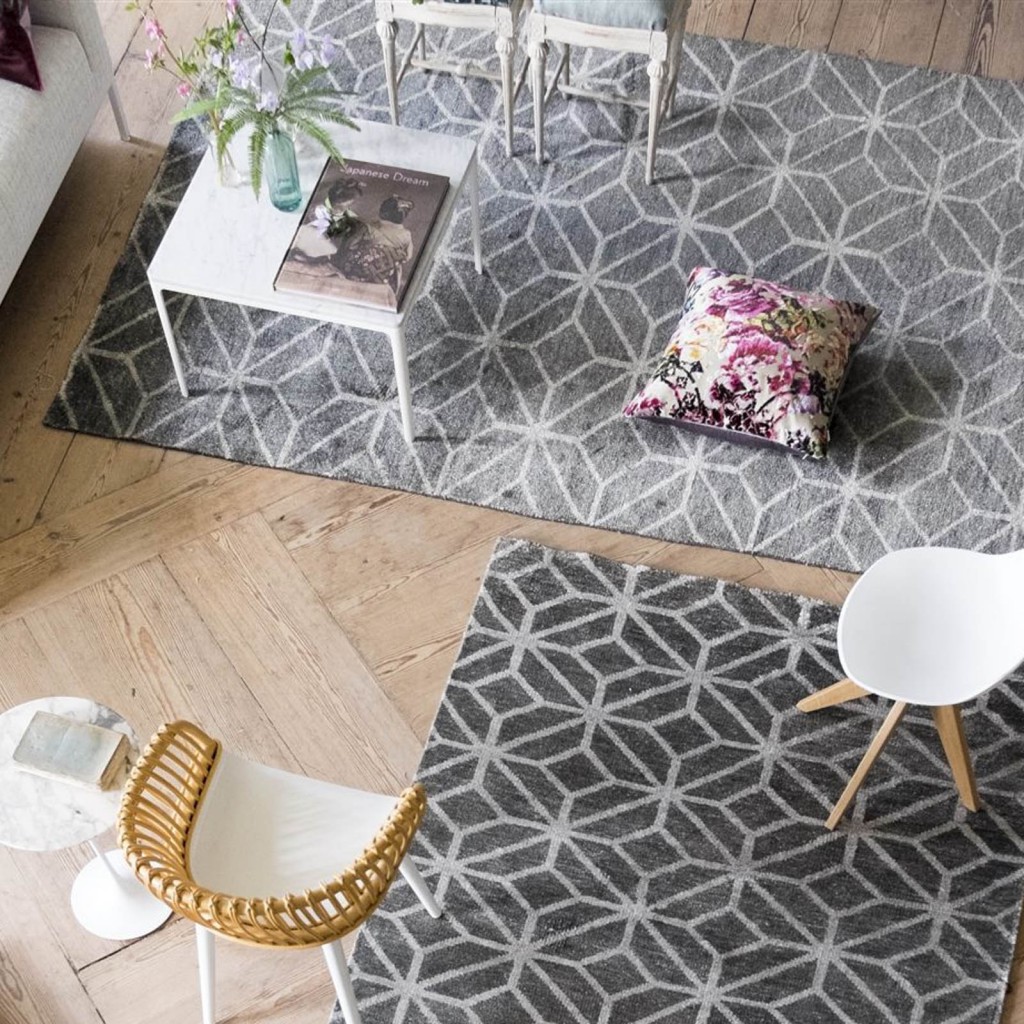 A bird's eye view of designer rug brand designers guild features two grey and white geometric rugs in a living room