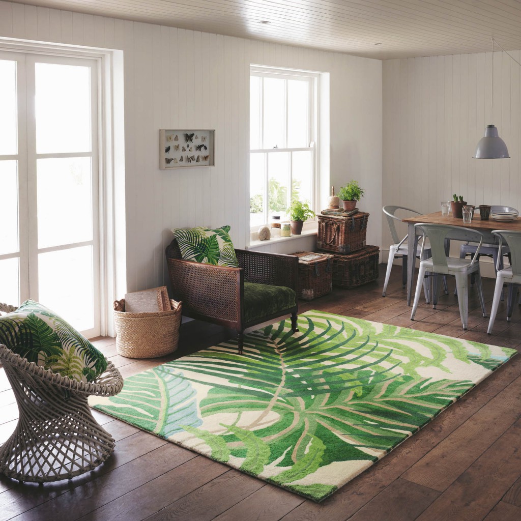 a tropical green rug lays on the floor of an open kitchen against a dark wood flooring designer rug brands Sanderson