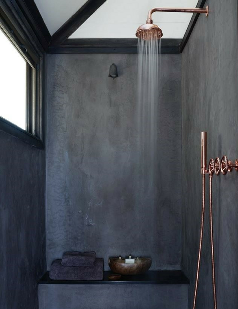 Dark concrete wetroom shower with copper interiors showerhead