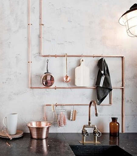 copper interiors with copper pipes and kitchen utensils against a white wall