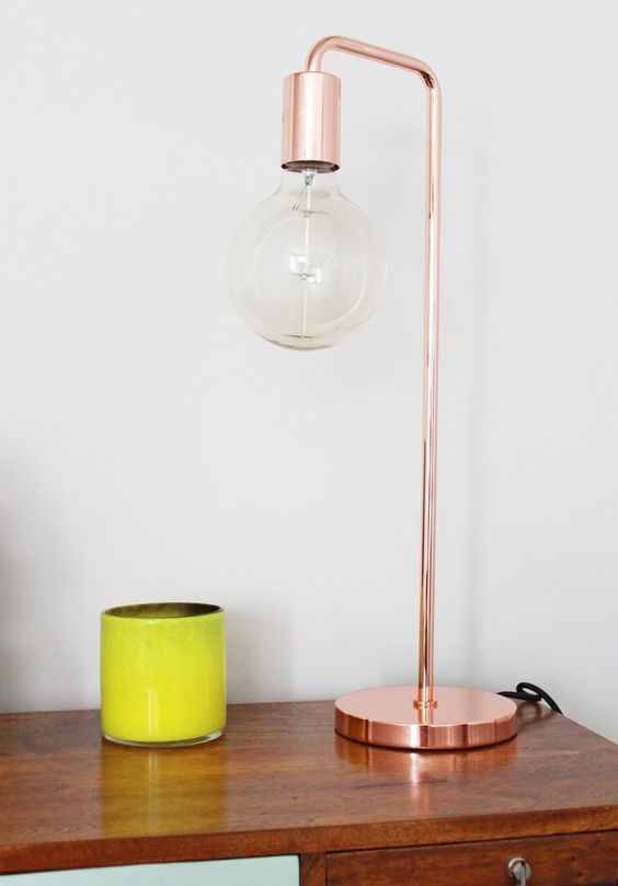copper base lamp on a wooden desk against a white wall for copper interiors
