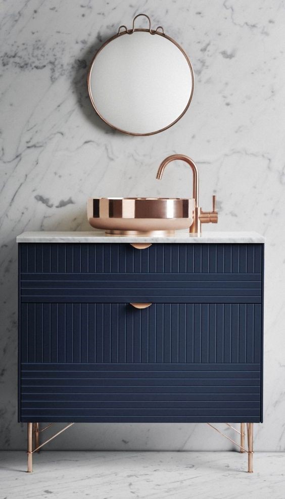 Marble style wall and dark blue bathroom cabinet with copper feet, handles and mirror for copper interiors