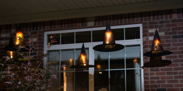 diy halloween decorations of floating witches hat hung on the front of a house with candle lights inside