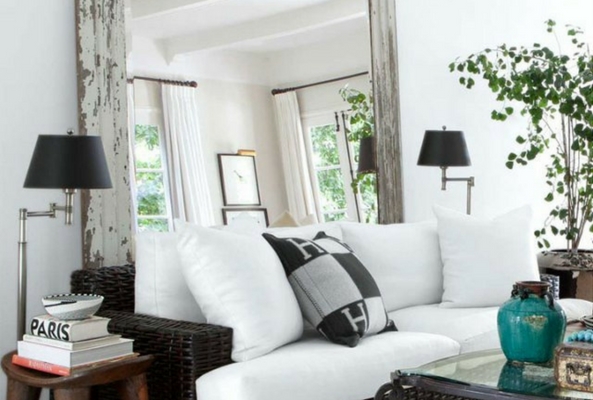 a small space using a large mirror in a living room space with white sofas