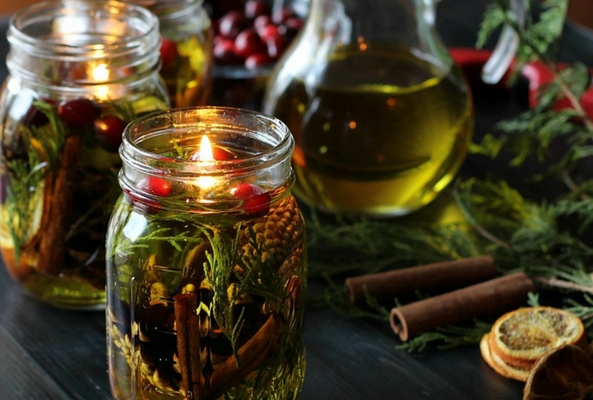 an olive oil candle filled with pine branches and berries to help a room smell like christmas