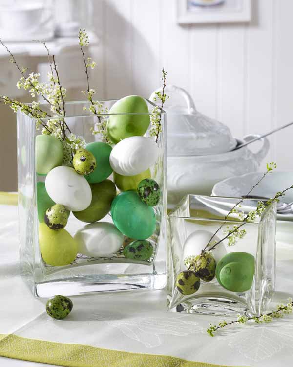 Glass vase filled with decorated eggs and twigs