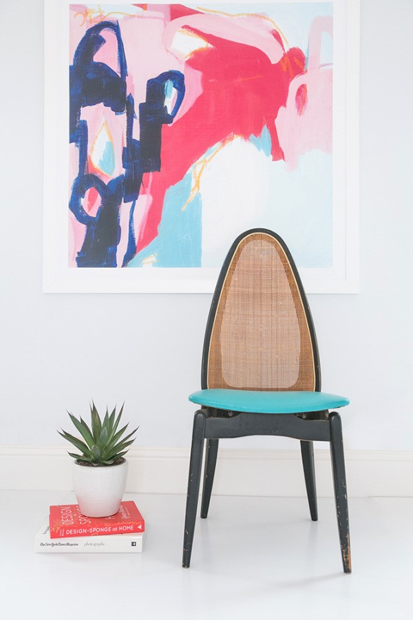 a minimalist room with a black and blue chair, a pink abstract painting and a small green summer succulent