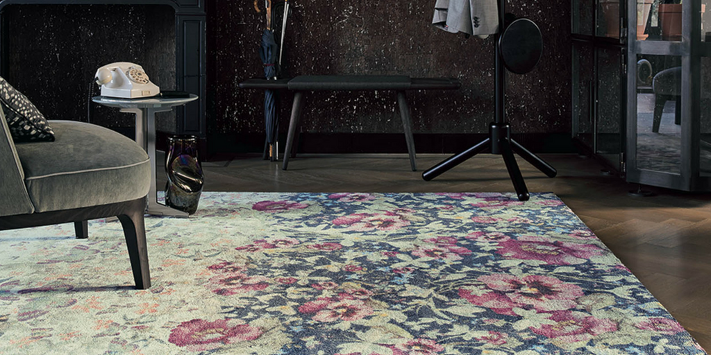 ted baker living room rug in a dark floral on a dark wooden floor with dark brown chairs on top next to a brightly lit window