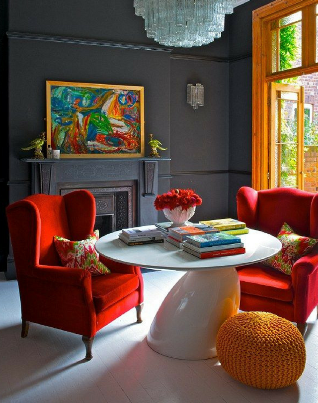 dark colours muted grey coloured walls in an unconventional dining room with red chairs