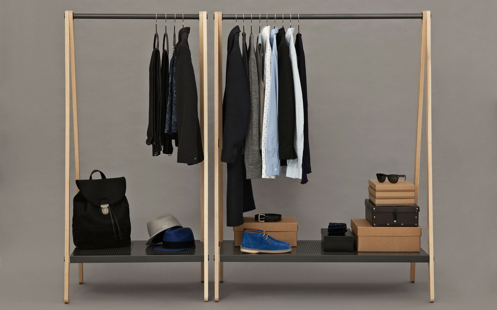 clothing rack with shoes, shirts, and sunglasses in a plain room