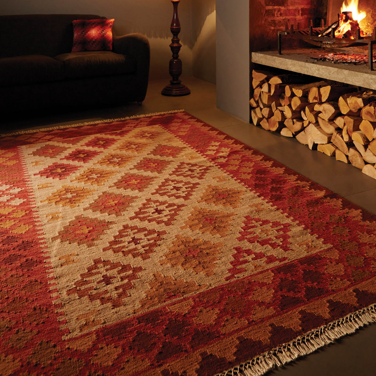 kilim rug on concrete floor next to fireplace and black couch