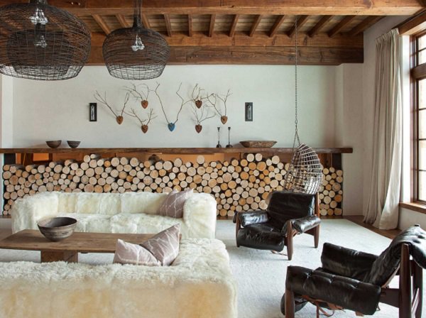 rustic interior design with firewood, exposed beams and a cream couch among other furniture