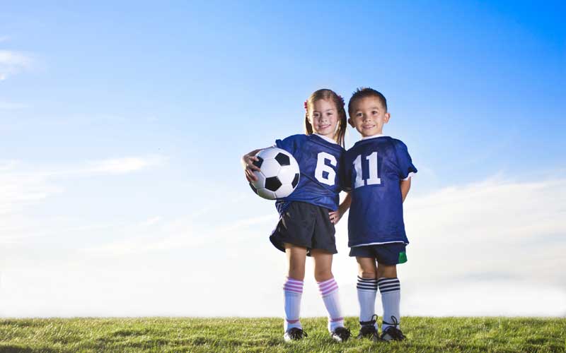 2 young children holding a football