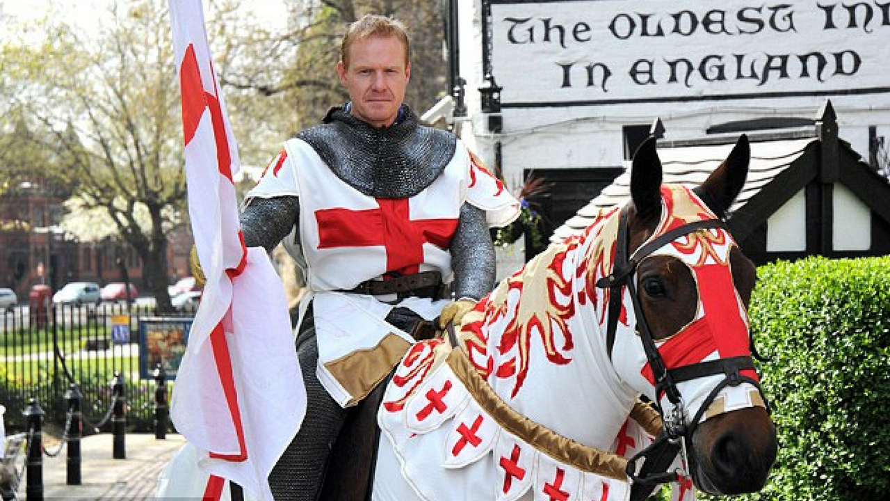 St. George's Day man dressed in medieval costume riding a horse and holding an England flag