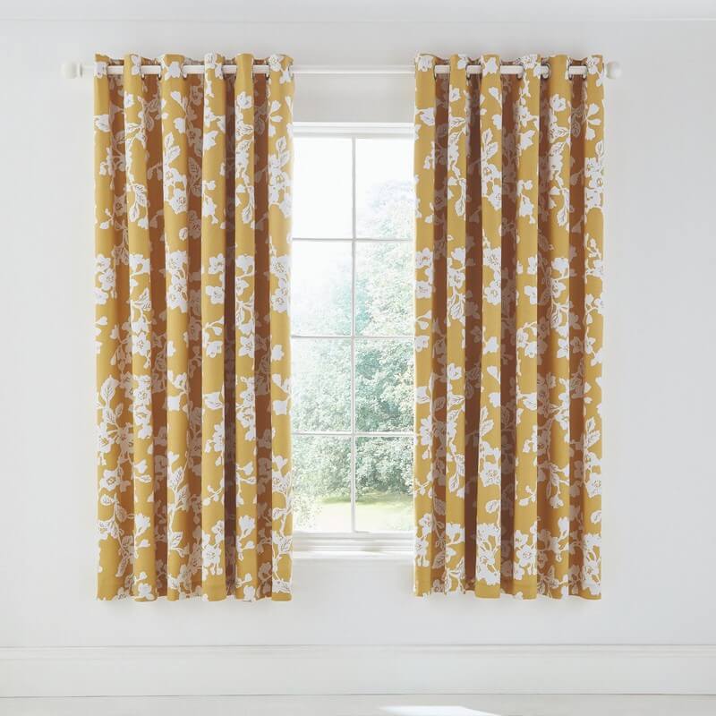 yellow and white floral curtains framing a window with a white wall 
