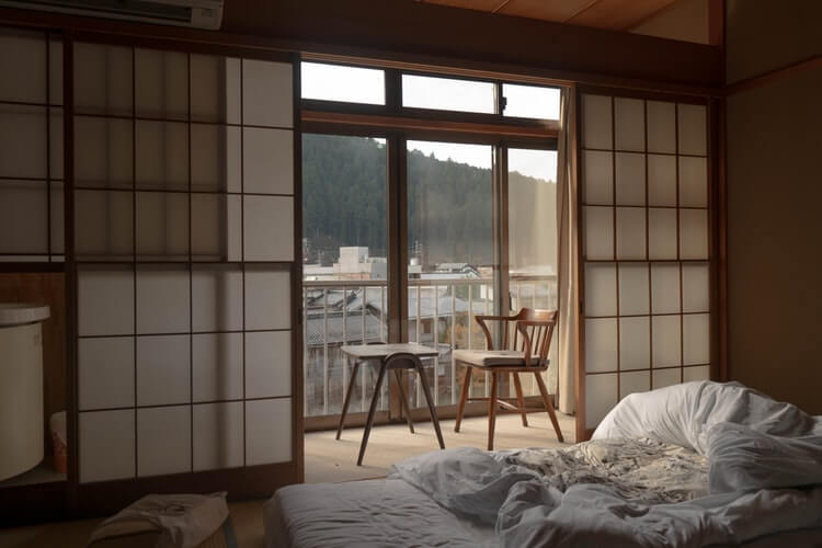 a japandi style room with sliding doors, pine wooden funiture and open windows overlooking nature