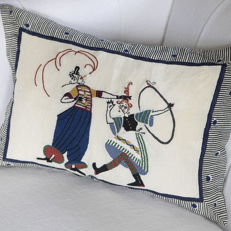 william yeoward circus day designer print cushion with old style figures embroidered with a striped outer design on a sofa