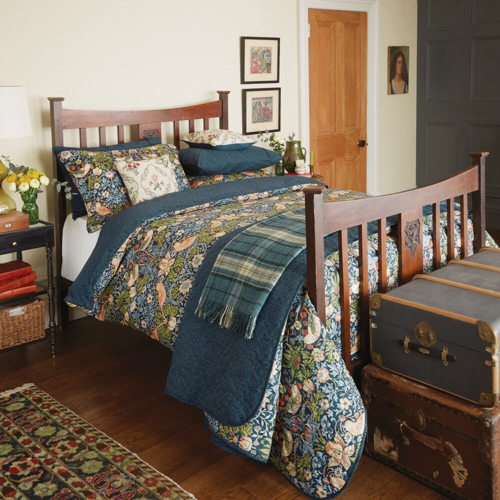 william morris strawberry print designer print bedding in an old style bedroom on a wooden bedframe