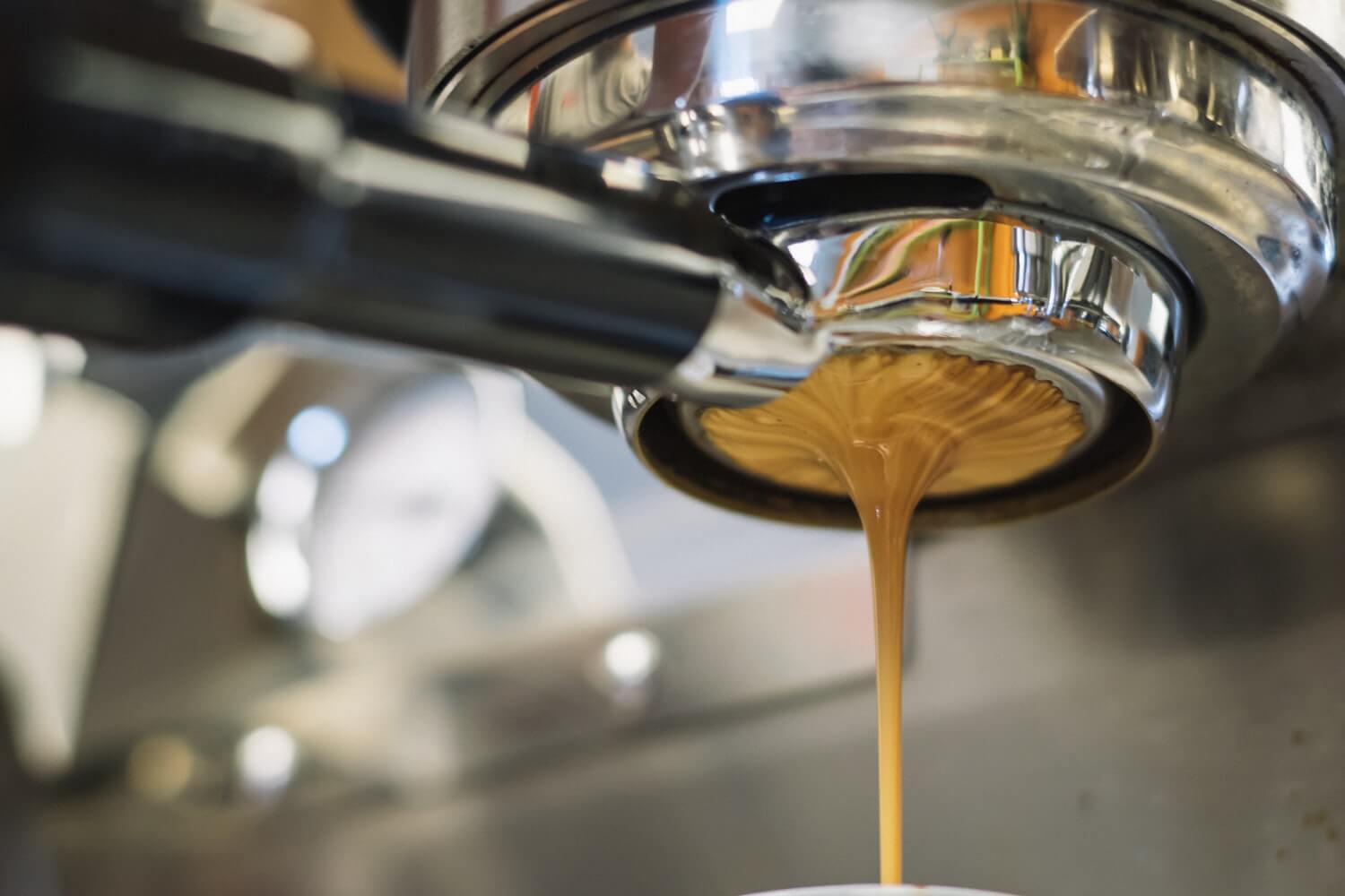 a close up image of coffee coming out of a coffee machine