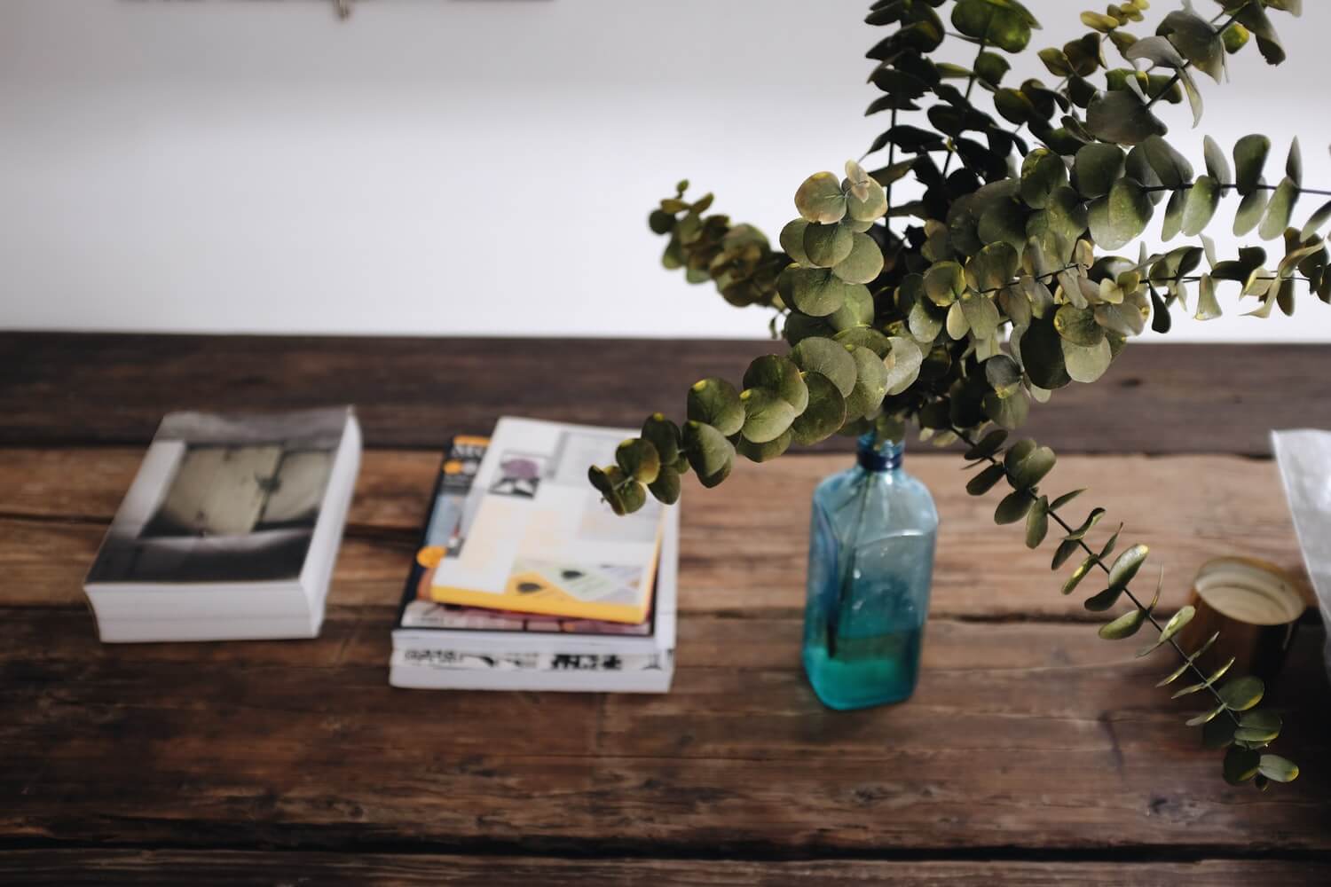 a dark wood table with eucalyptus leaves and books on top