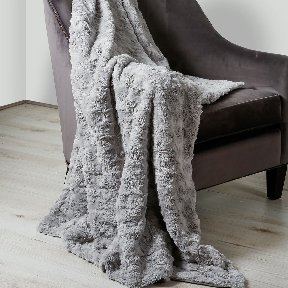 the hepburn faux fur throw in silver draped over an arm of a chair