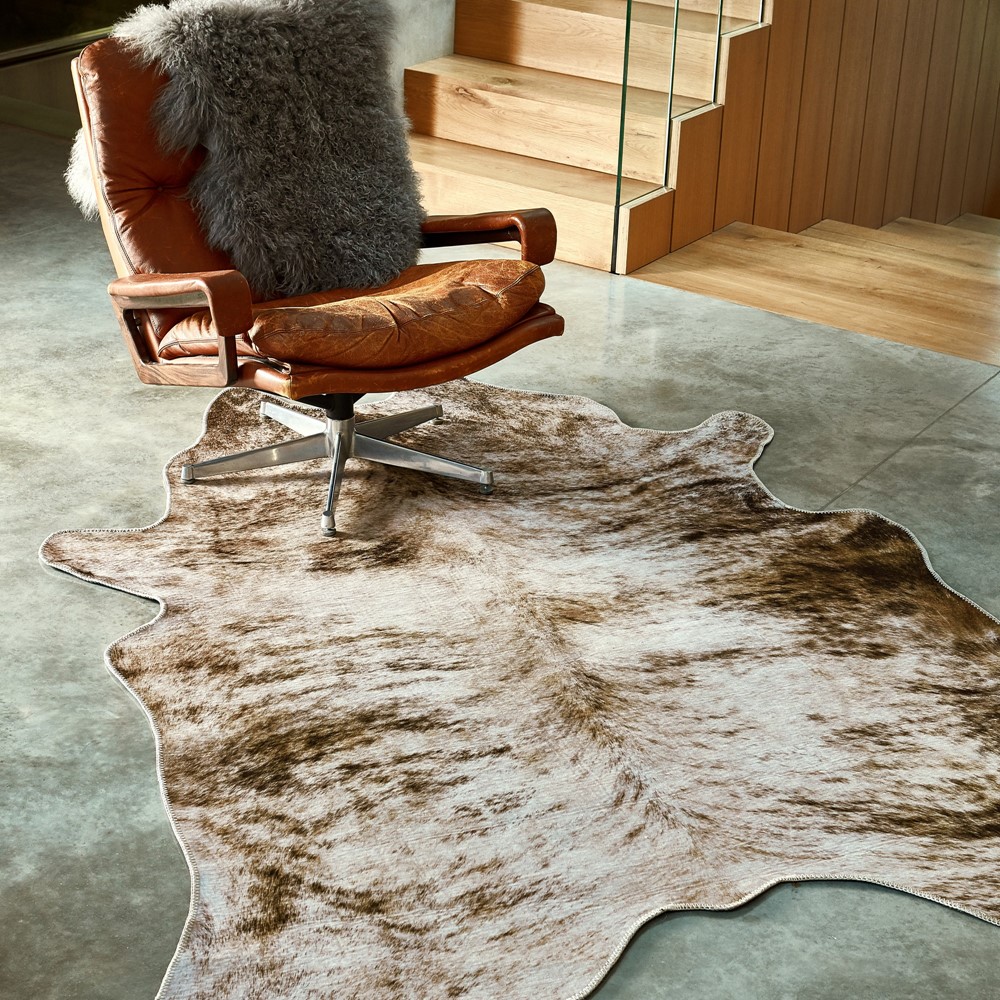 a cowhide rug with an office chair sat on top in a brightly lit room