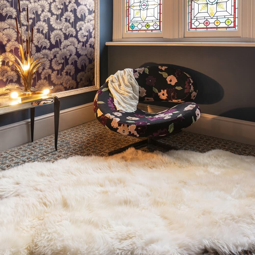 a sheepskin rug laid on the floor of a living room with an armchair and patterned wall behind