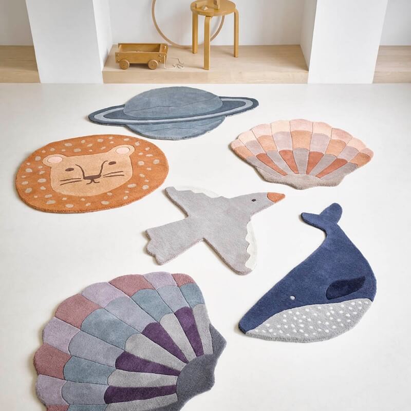 six brink and campman wool rugs for kids are on the floor, consisting of a lion, planet, shells, bird and whale