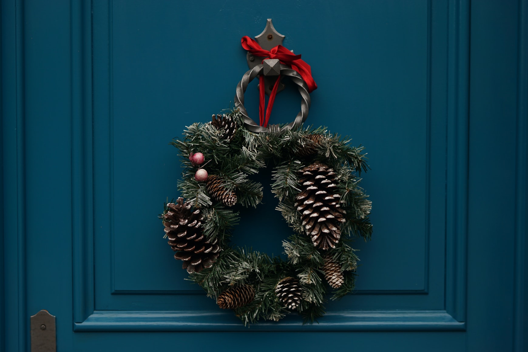 a christmas wreath is laid on a dark teal door