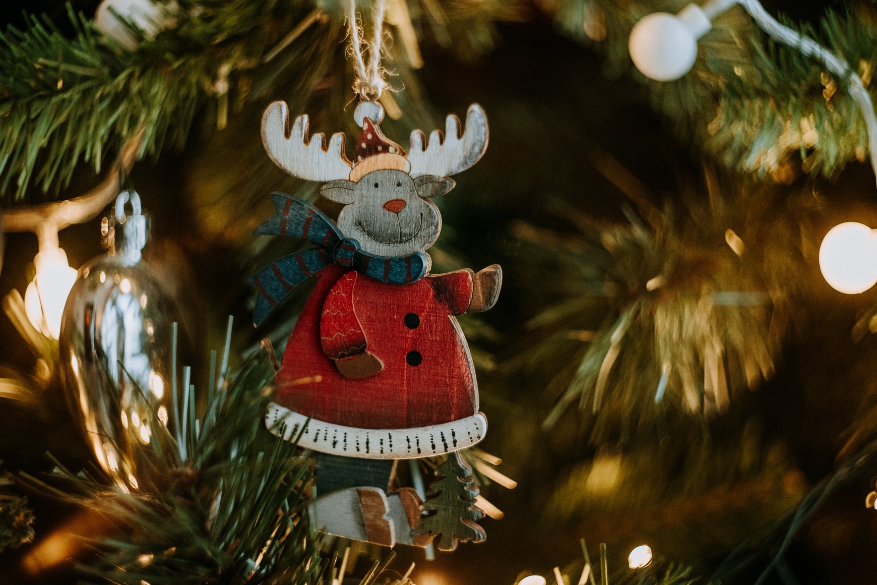 a wooden reindeer ornament hanging from a Christmas tree branch