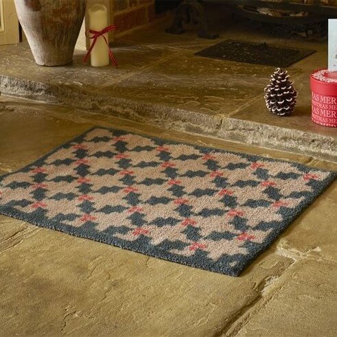 the geometric holly doormat is set in front of a fireplace on concrete flags in a house