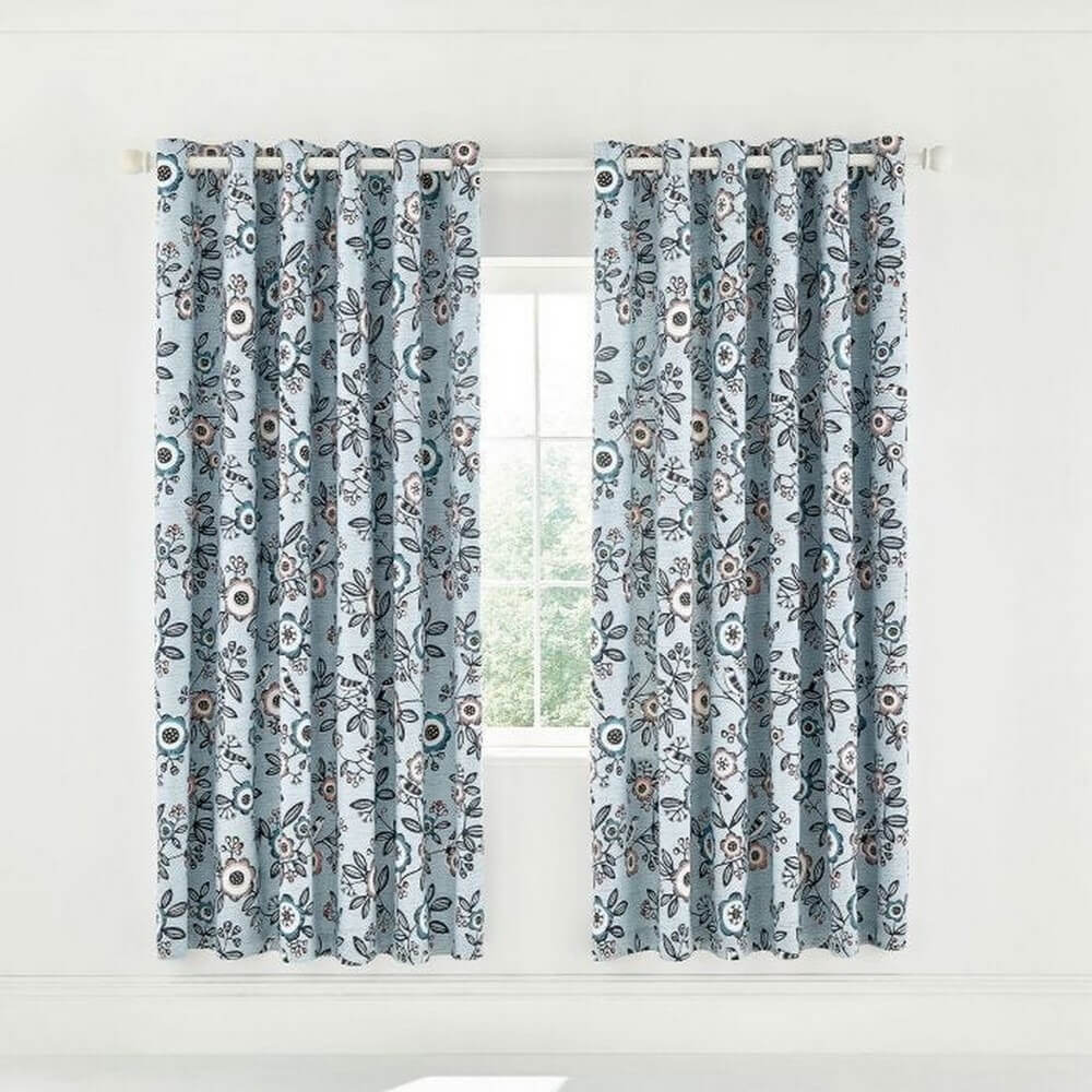 blue curtains set up by a window with floral and bird patterns on it in dulux's colour of the year