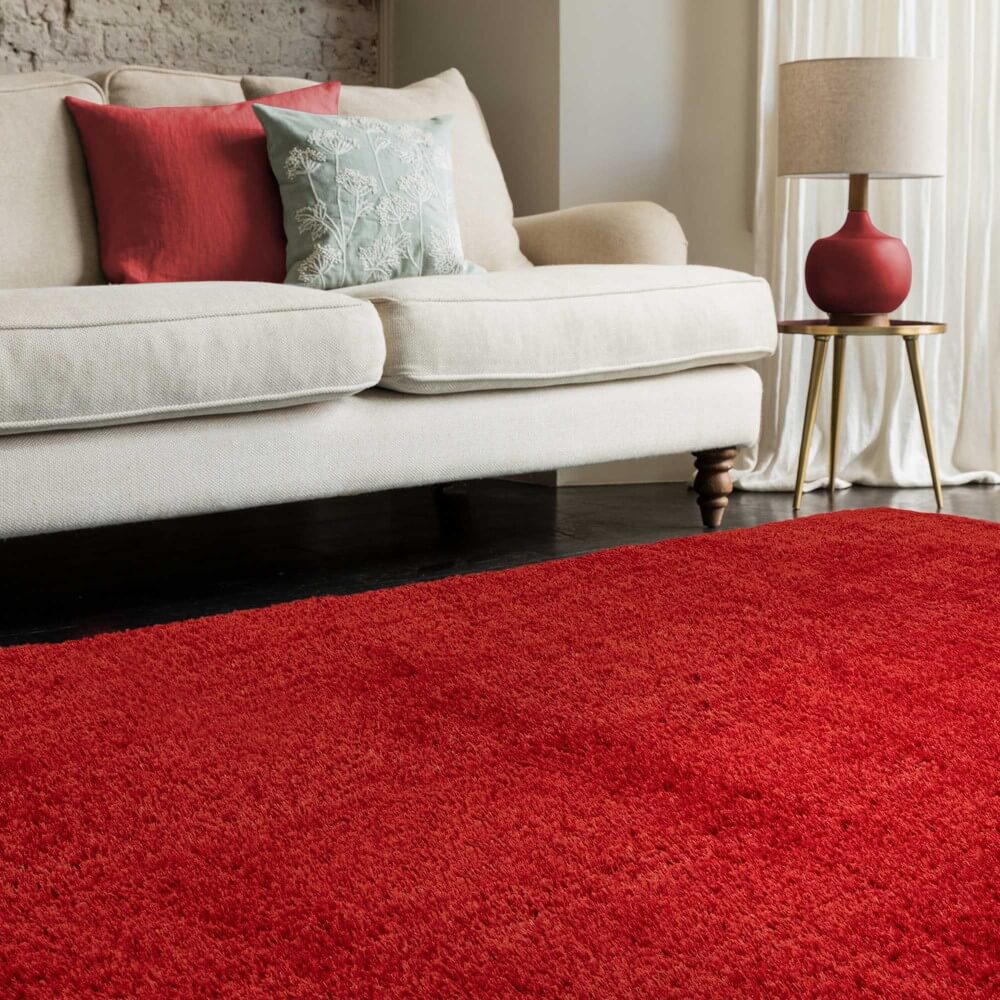 a red shaggy rug on the floor in a house in front of a beige sofa