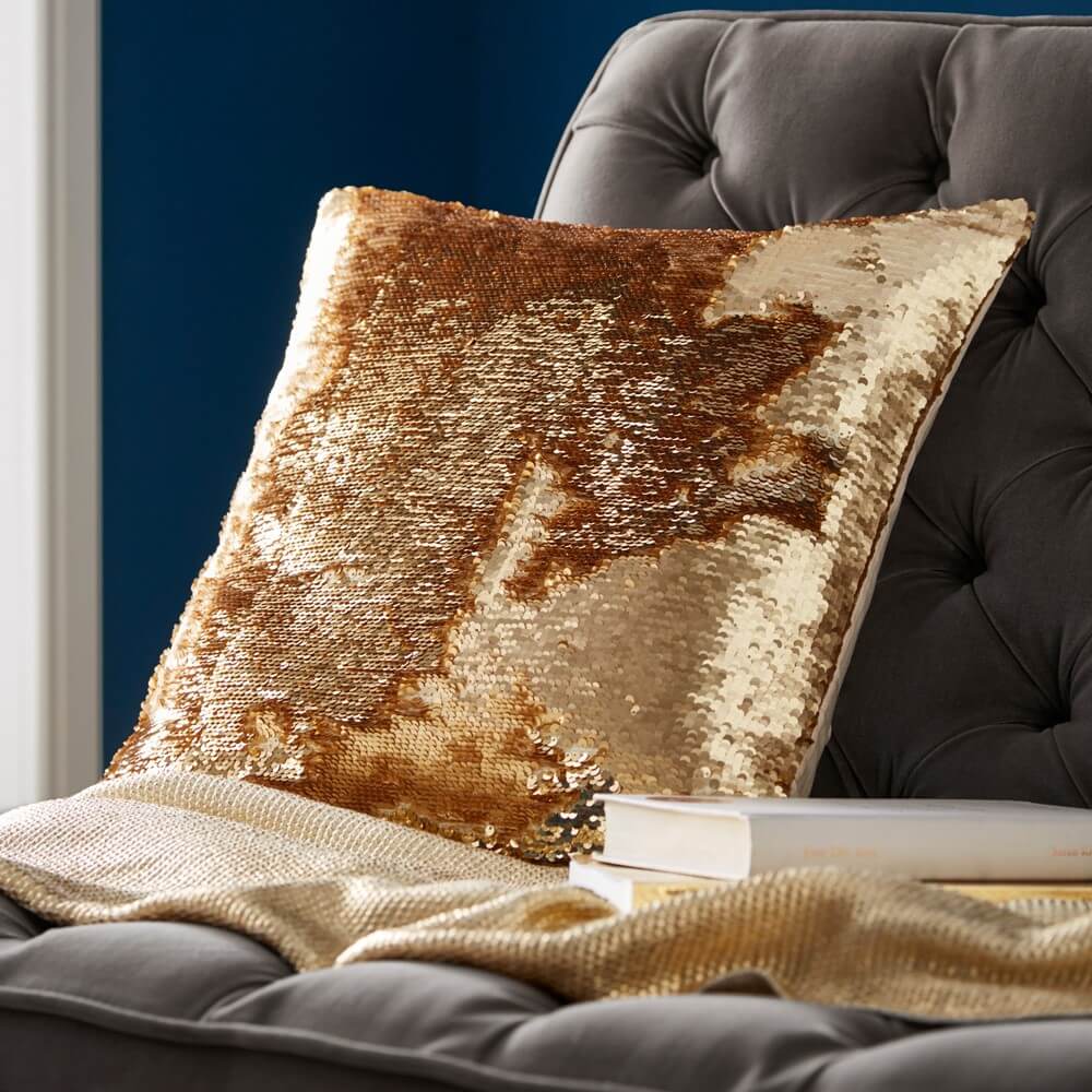 gold sequin cushion placed on a bed in a home