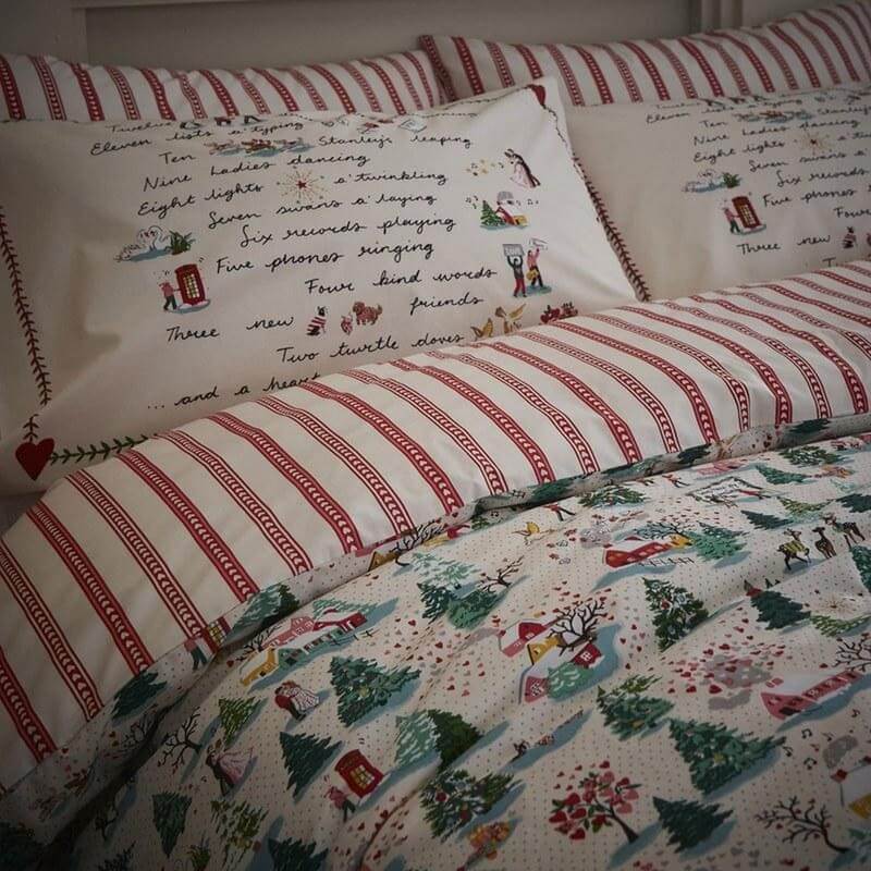 a close up of the cath kidston bedding on a bed with red stripes under the duvet and christmas figures on the bedding