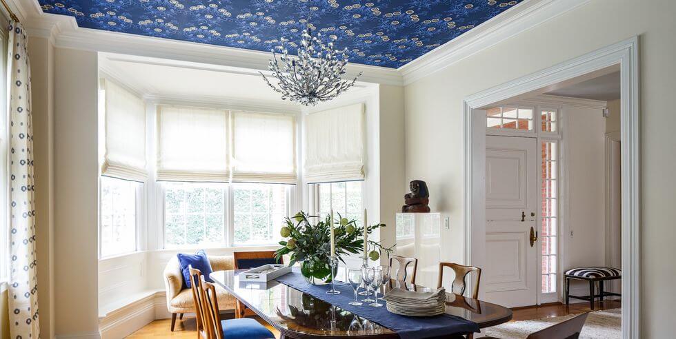 a dining room with blue patterened walpaper used creatively on the ceiling 