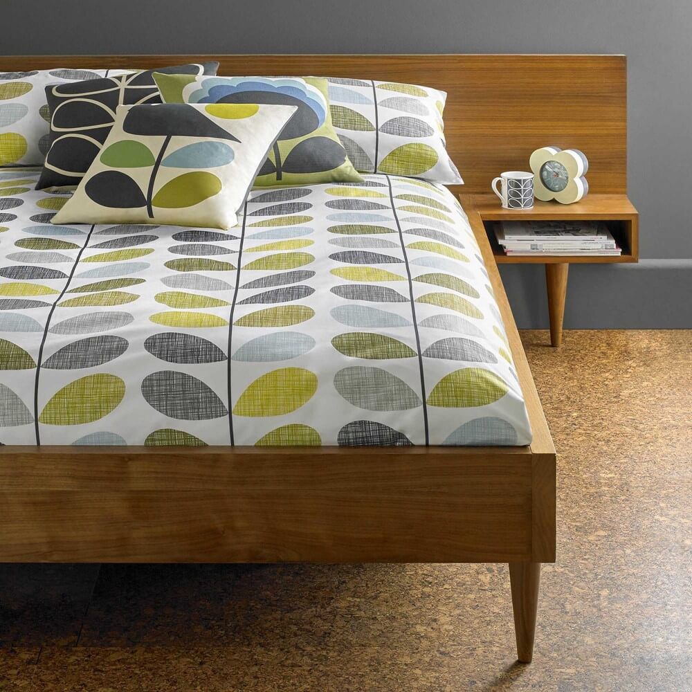 Scribble stem bedding in green and blue on a wooden bedframe in a minimal room