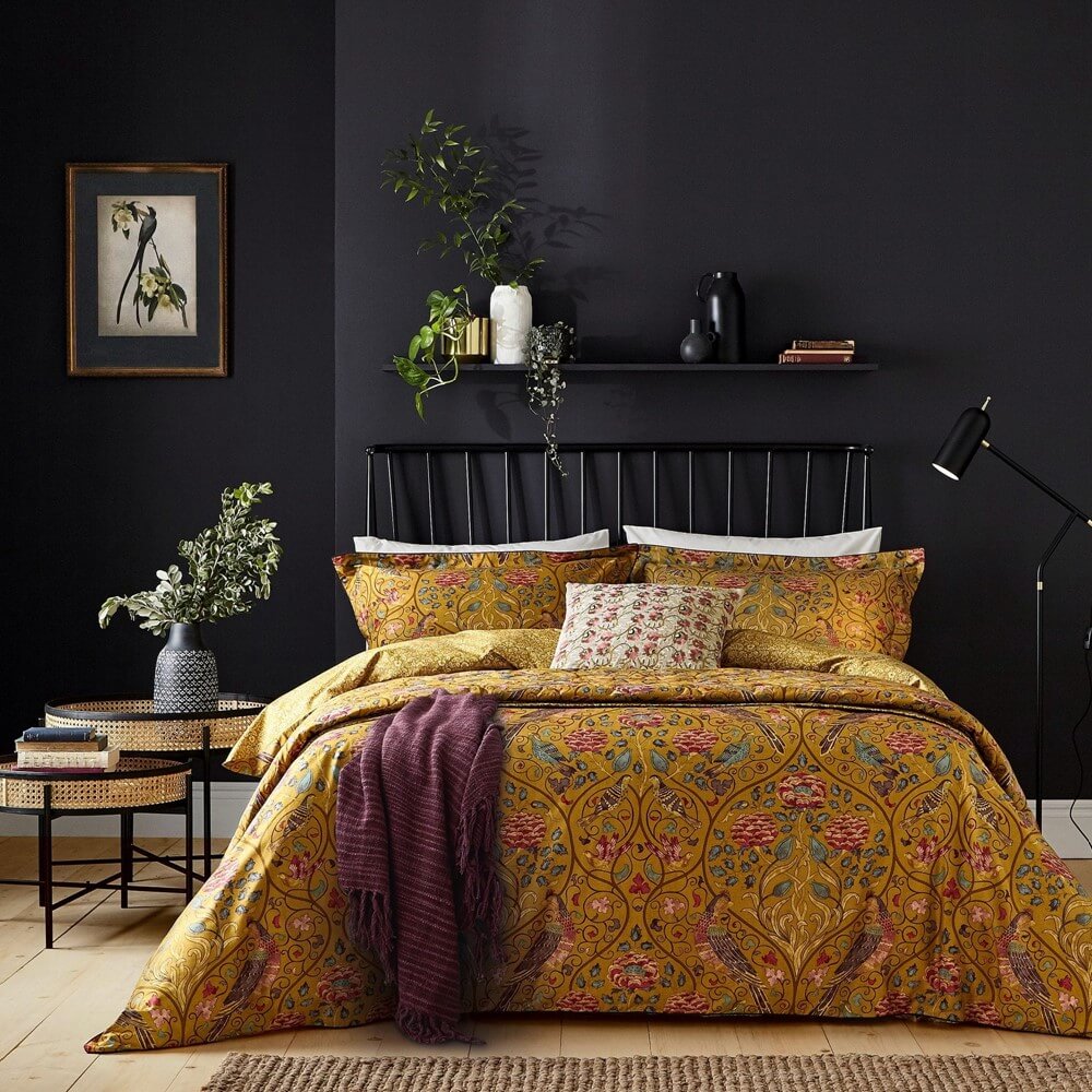 a luxurious bedding set in orange floral print is on a bed in a darkly painted bedroom