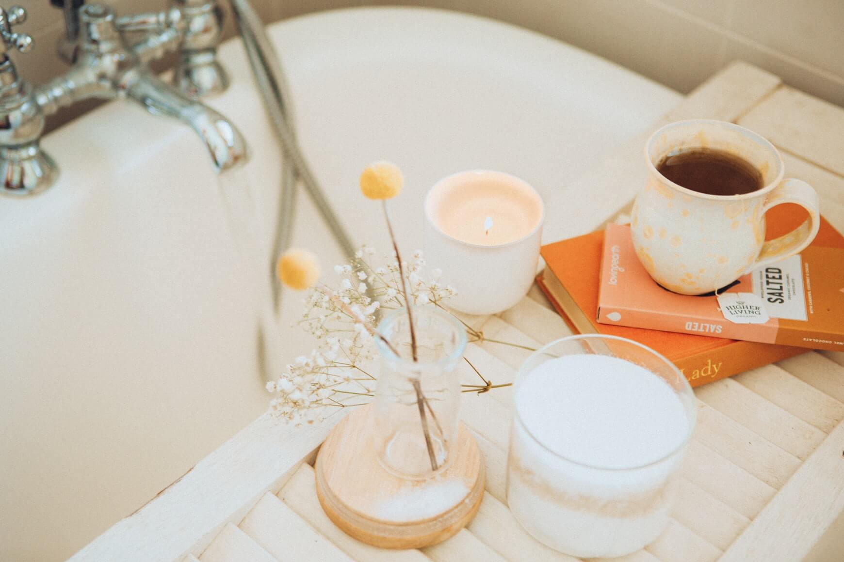 a close up image of a bath with a tray over it with a candle to help you sleep better