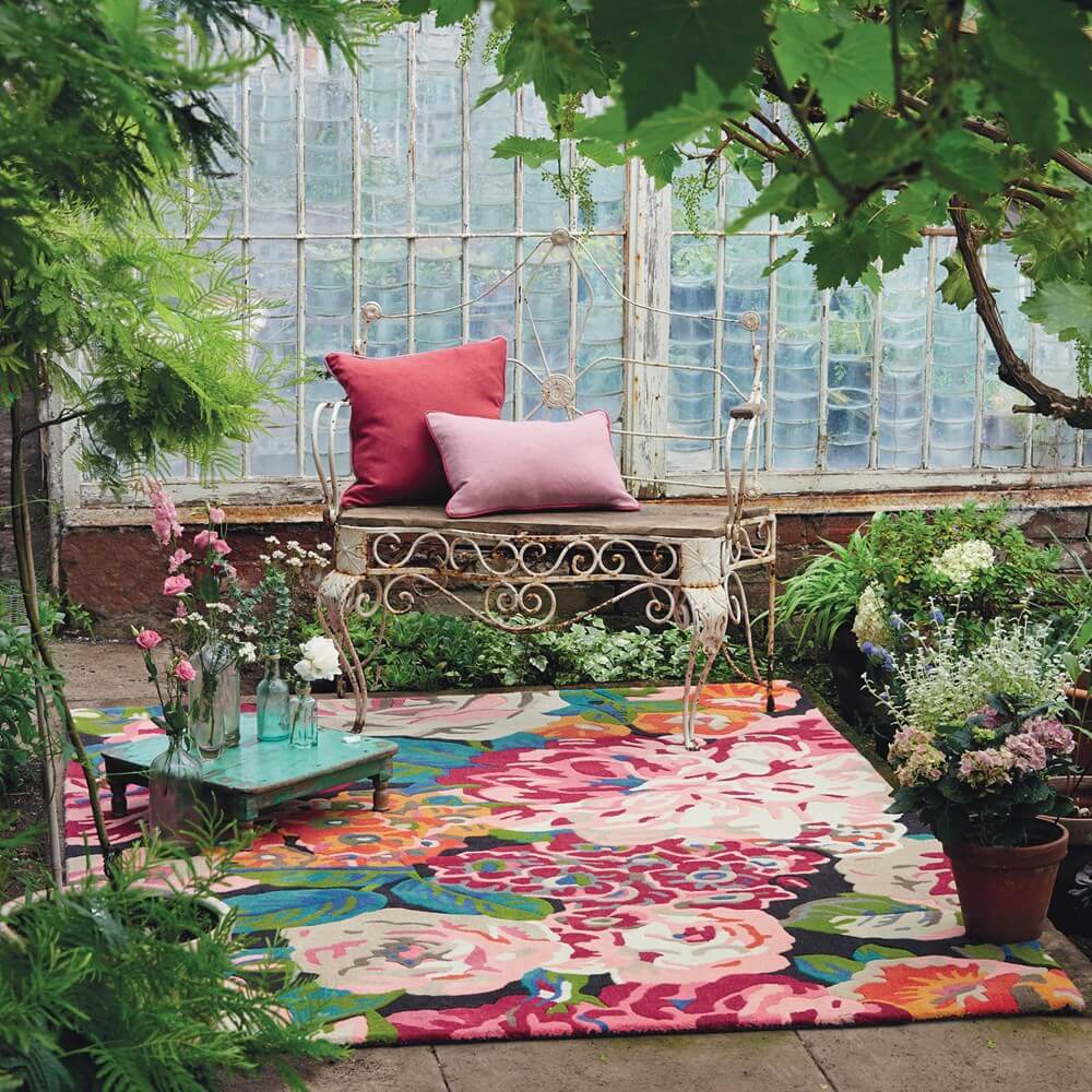 rose and peony floral rug in a conservatory with lots of plants