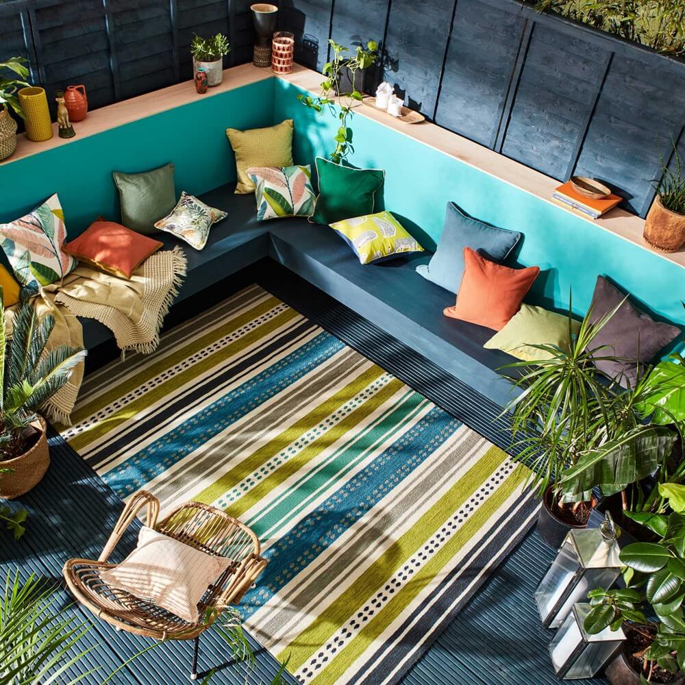 Scion Kiwi rug is outdoors in bright striped pattern surrounded by outdoor furniture on a decking