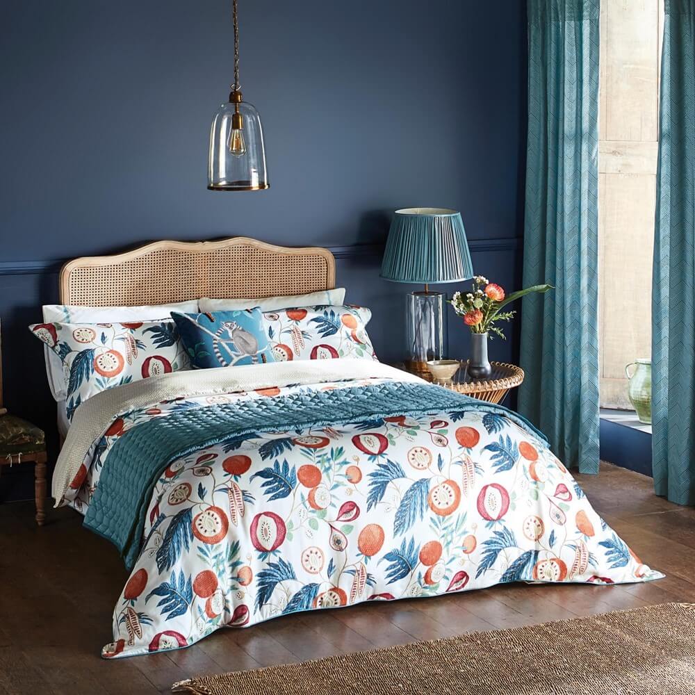 a blue toned bedroom with bedding set featuring brightly coloured jackfruit