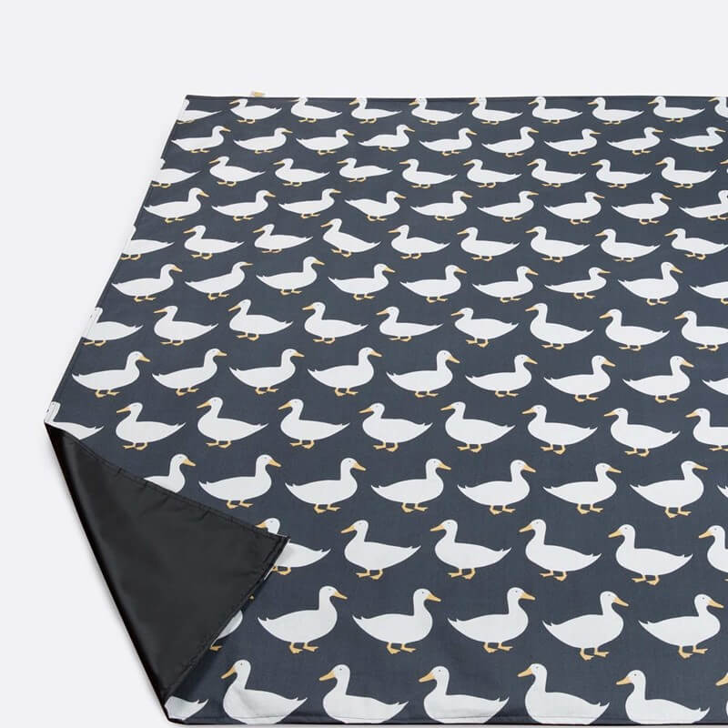 navy pincic blanket on a white floor with white puddle duck motifs repeated on the style