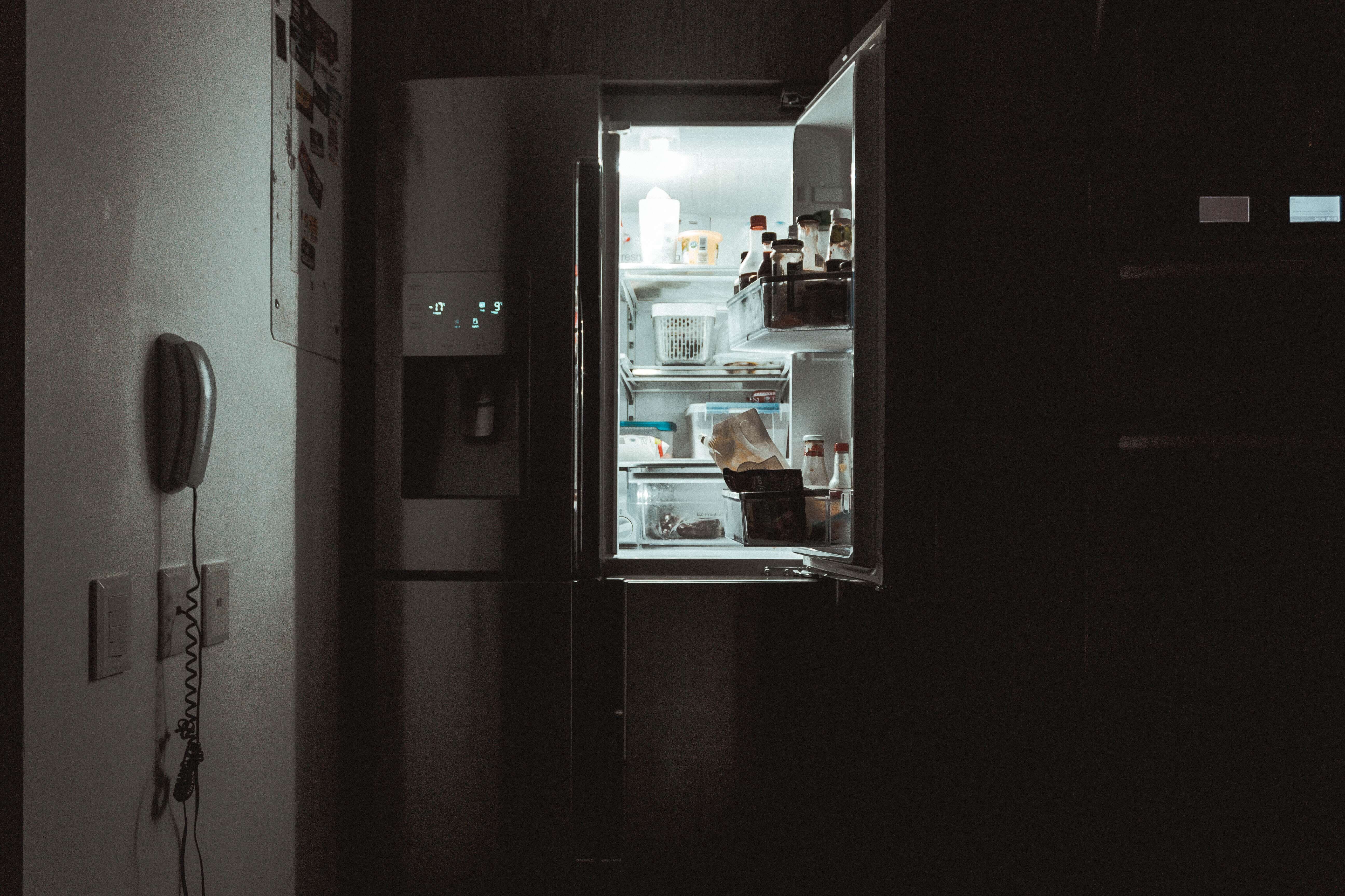 a dark kitchen lit up with the light of an open fridge