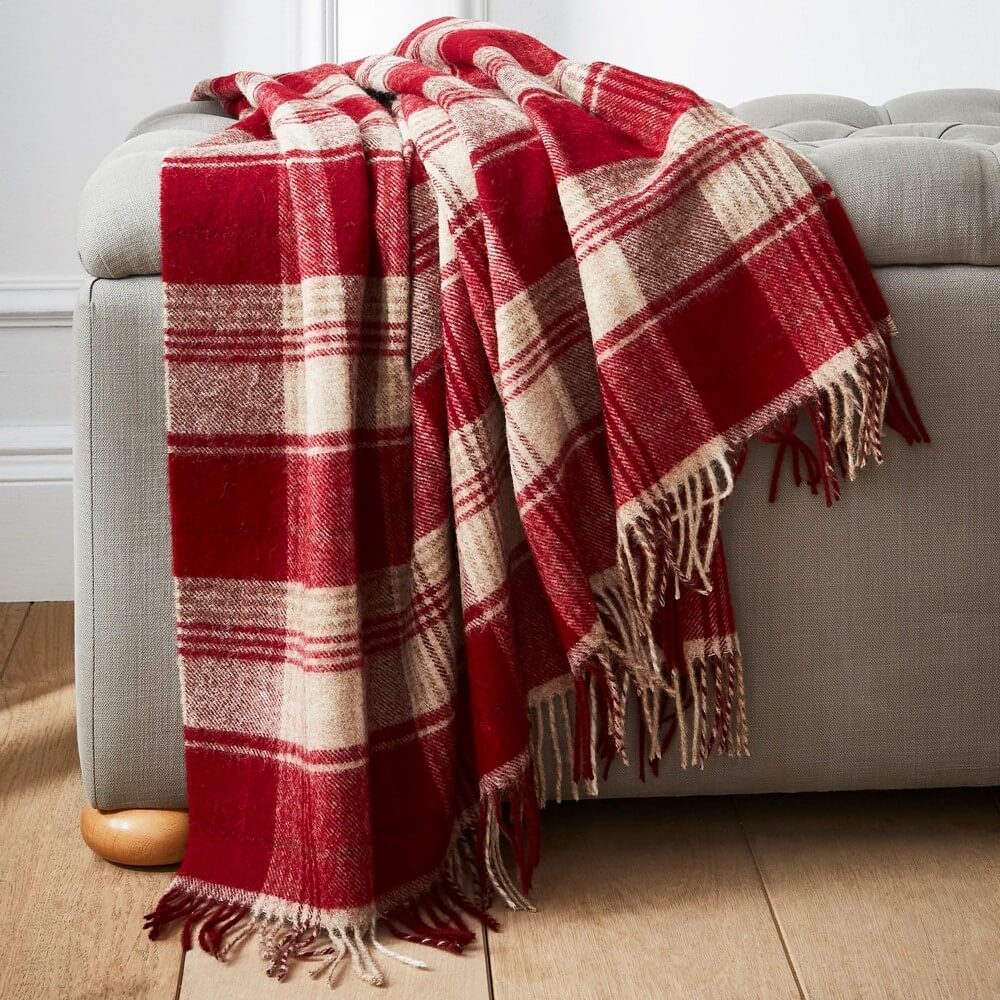a red tartan rug draped over a sofa for ways to keep warm this winter