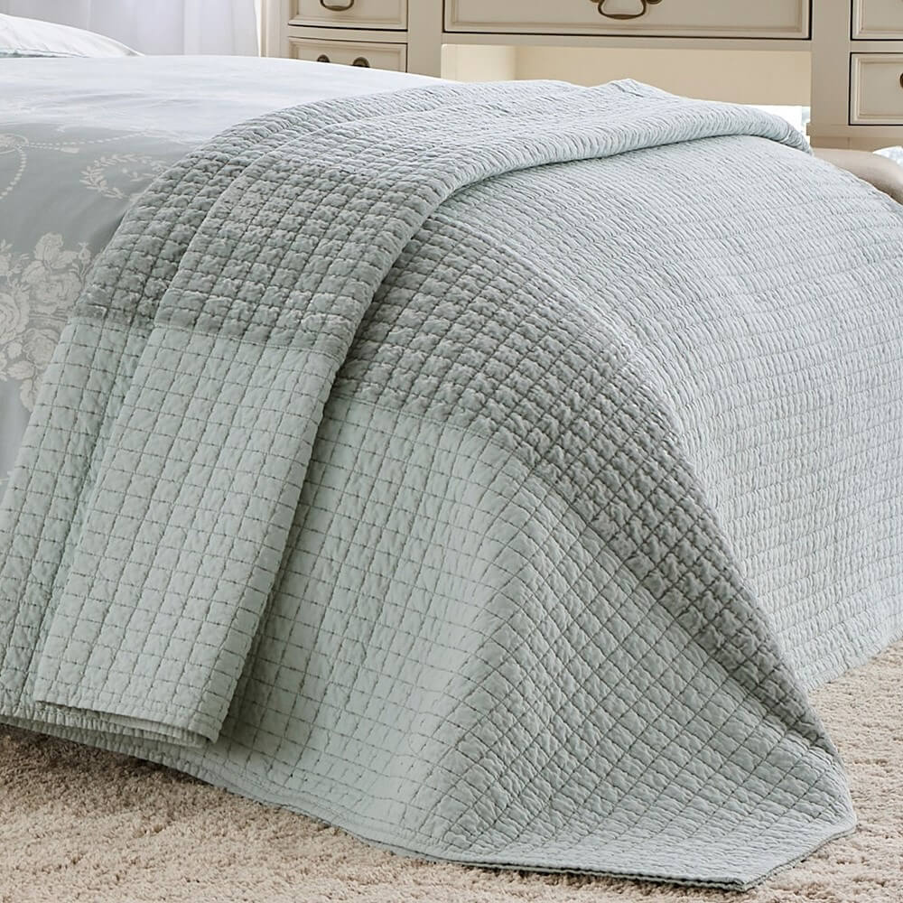 Quilted throw in duck egg blue on a bed