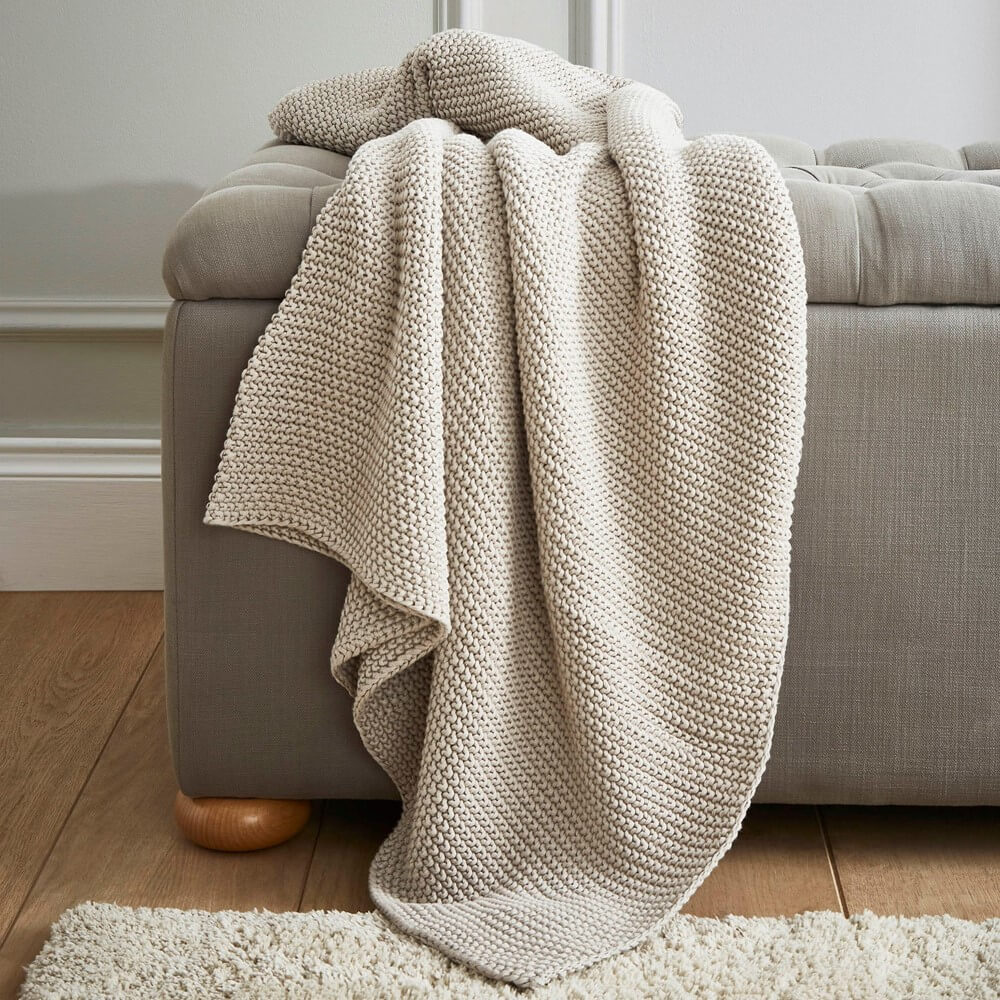 Laura Ashley chunky blanket draped over a sofa as a cosiest throw