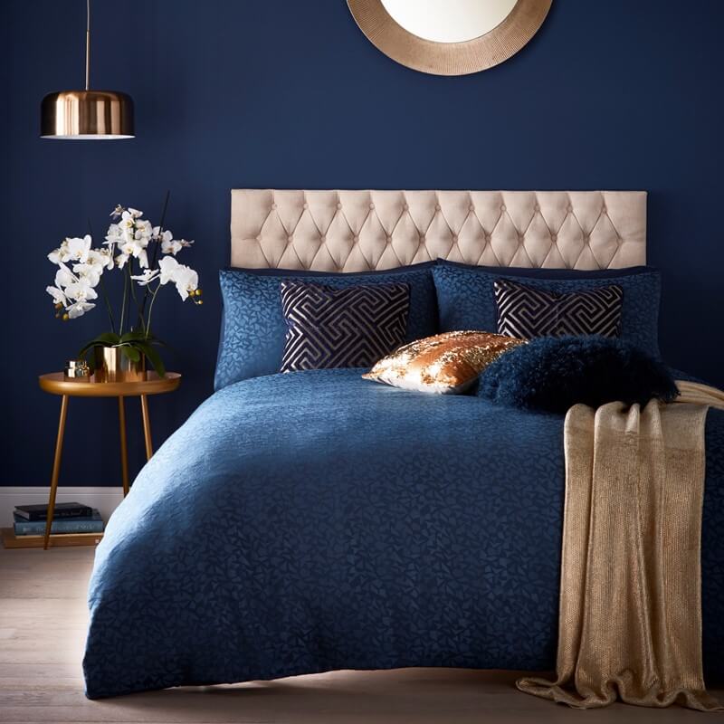 Gold tess daly blanket on a dark blue bed